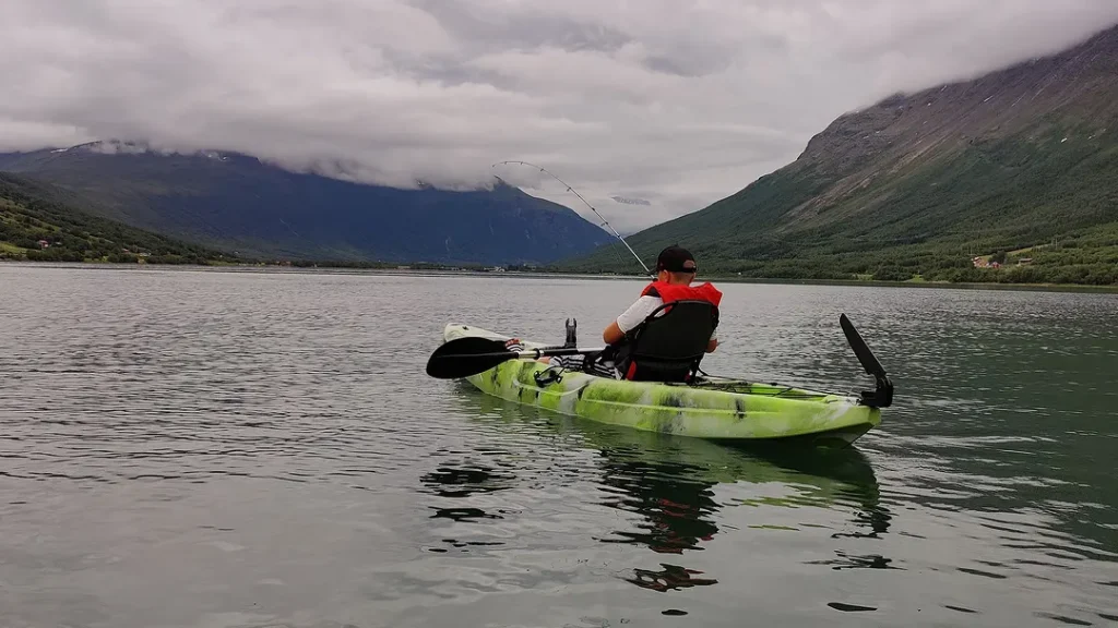 A guest fishing from a kayak on a grey summer fjord