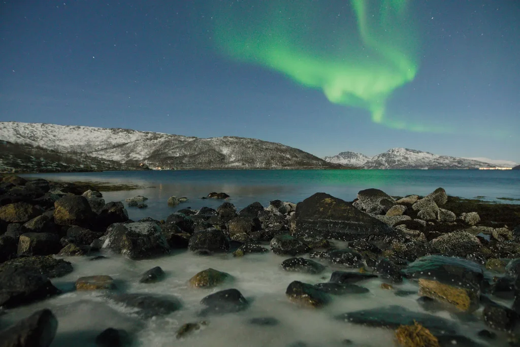 Northern lights over a rocky shore near Nordkjosbotn
