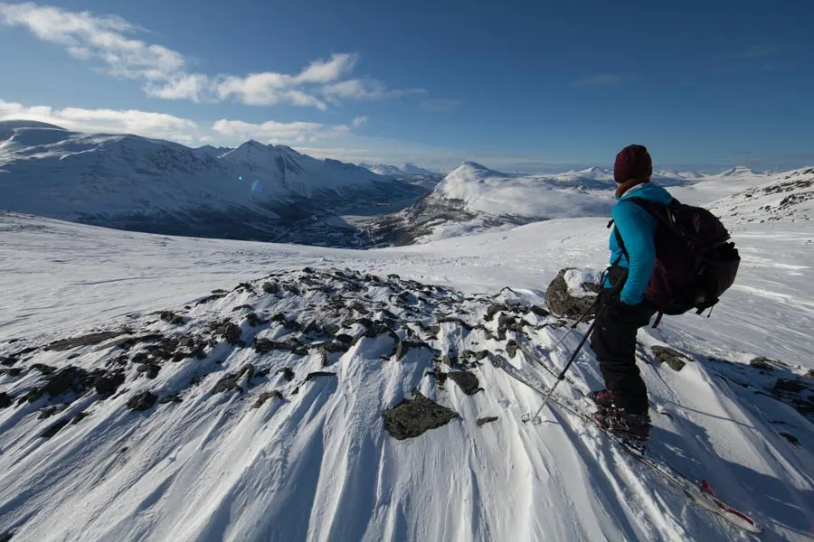 A hiker on a snowy summit on a clear day