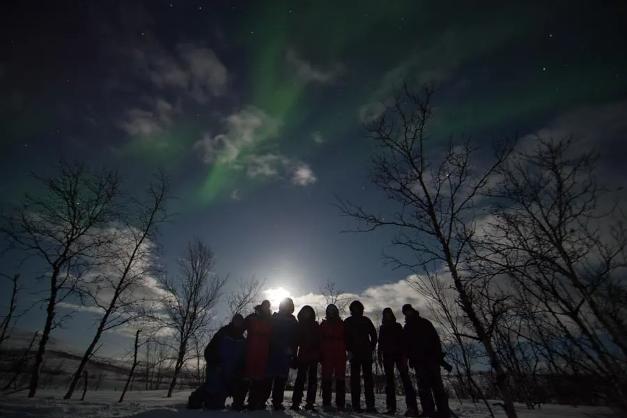 A group under the moon and the northern lights